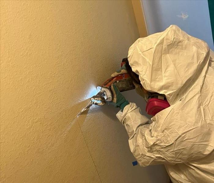 crew member cutting hole in the wall